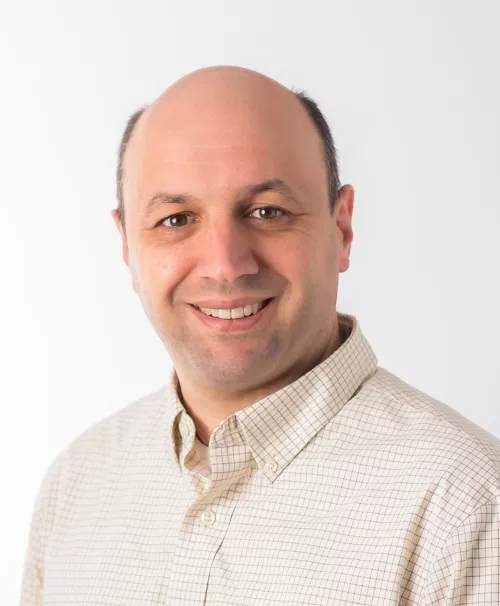 balding man smiling with a white shirt against an industrial background